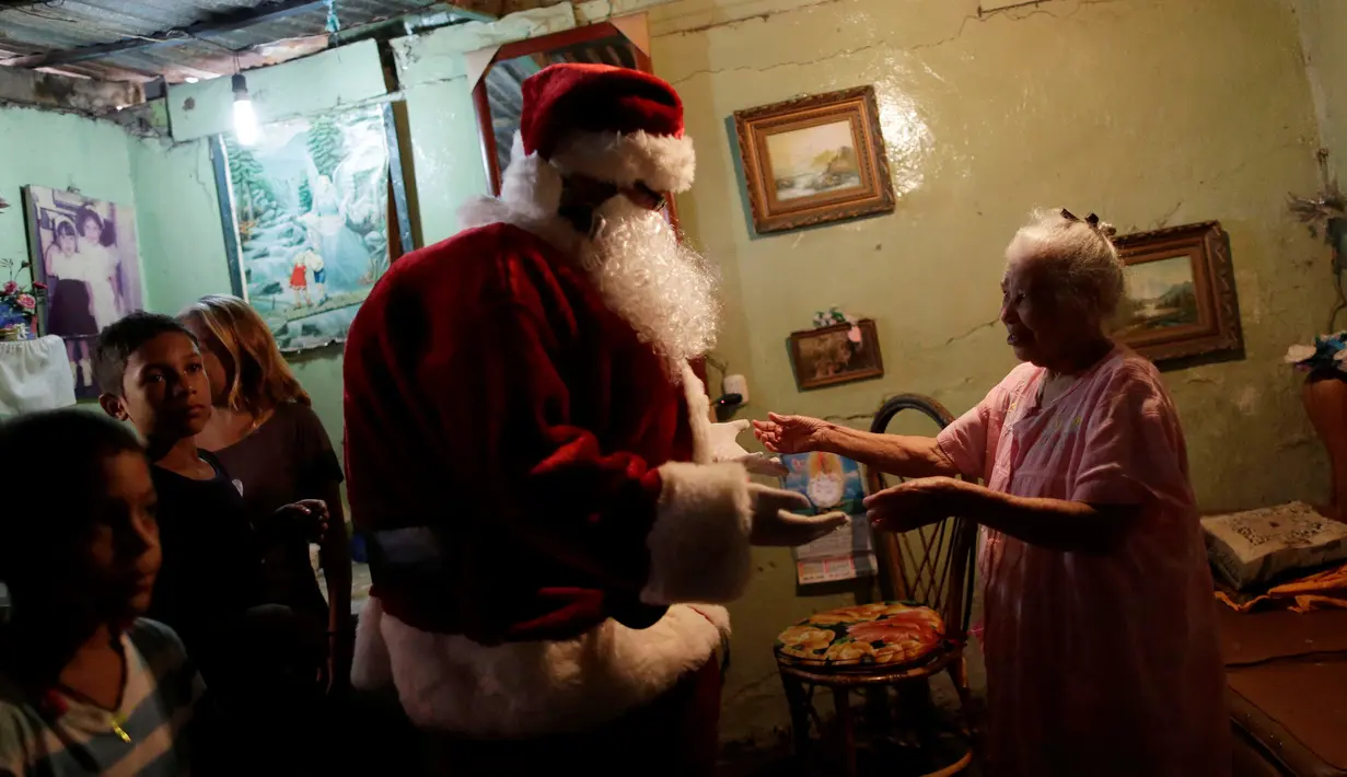 Santa Claus berbincang dengan seorang wanita di kawasan kumuh Petare di Caracas, Venezuela (11/12). (Reuters/Ueslei Marcelino)