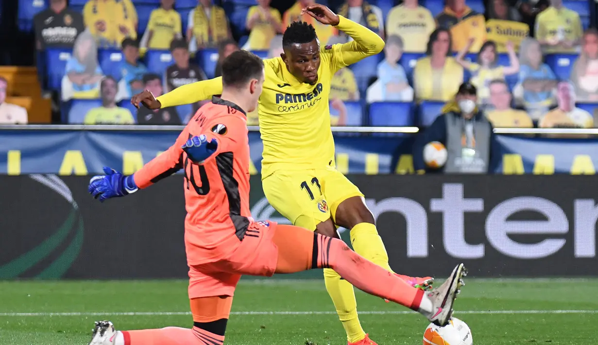 Gelandang Villarreal, Samuel Chukwueze (kanan) melepaskan tendangan yang coba dihadang kiper Dinamo Zagreb, Dominik Livakovic dalam laga leg kedua perempatfinal Liga Europa 2020/2021 di La Ceramica Stadium, Villarreal, Kamis (15/4/2021). Villarreal menang 2-1 atas Dinamo Zagreb. (AFP/Jose Jordan)