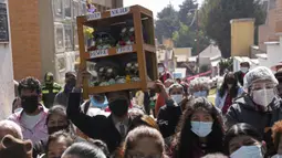 Seseorang membawa sekotak tengkorak manusia yang dihias di Pemakaman Umum untuk diberkati oleh seorang imam pada Festival Natitas di La Paz, Bolivia, Selasa (8/11/2022). Tradisi tahunan ini merayakan kematian di Bolivia dengan tengkorak yang dirawat dan didekorasi oleh mereka yang menggunakannya sebagai jimat untuk perlindungan. (AP Photo/Juan Karita)