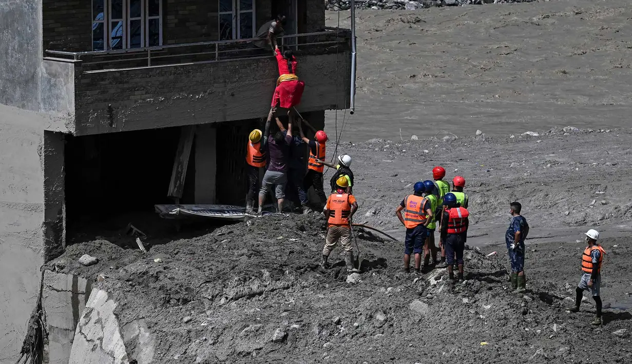Personel kepolisian mengevakuasi warga yang terjebak dari sebuah rumah yang tertimbun lumpur akibat banjir bandang di Trishuli, Distrik Nuwakot, Nepal, Kamis, pada 27 Agustus 2026. (AFP/ Arun Sankar)