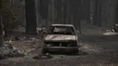 Sebuah mobil dan pohon-pohon yang terbakar hancur dalam Kebakaran Dixie Fire di daerah Air Terjun India di Plumas County, California (26/7/2021). Kebakaran terjadi sejak 14 Juli itu telah meratakan lebih dari selusin rumah dan bangunan lainnya ketika melahap kota kecil Indian Falls. (AFP/Robyn Beck)