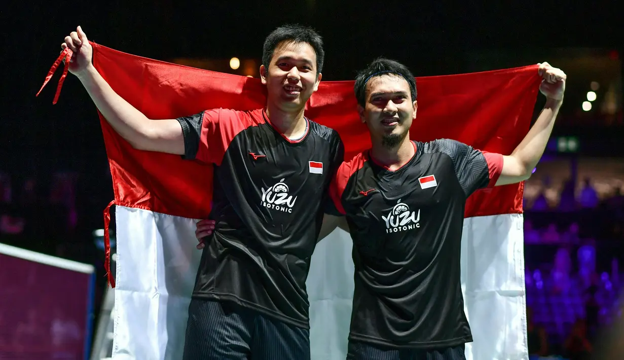 Ganda Putra Indonesia Hendra Setiawan (kiri) dan Mohammad Ahsan membawa bendera Merah Putih usai memenangi babak final Kejuaraan Dunia Bulu Tangkis 2019 di St. Jakobshalle, Basel, Swiss, Minggu (25/8/2019). Ganda Putra Indonesia menang 25-23, 9-21, 21-15 atas ganda Jepang. (FABRICE COFFRINI/AFP)