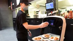 Pelayan memasukkan nomor meja untuk pengantaran robot di restoran Asia di Wina, Austria, Kamis (28/5/2020). Restoran tersebut menggunakan robot untuk mengantar makanan guna mengurangi kontak yang tidak diperlukan antara pelayan dan pelanggan di tengah pandemi virus corona COVID-19. (Xinhua/Guo Chen)
