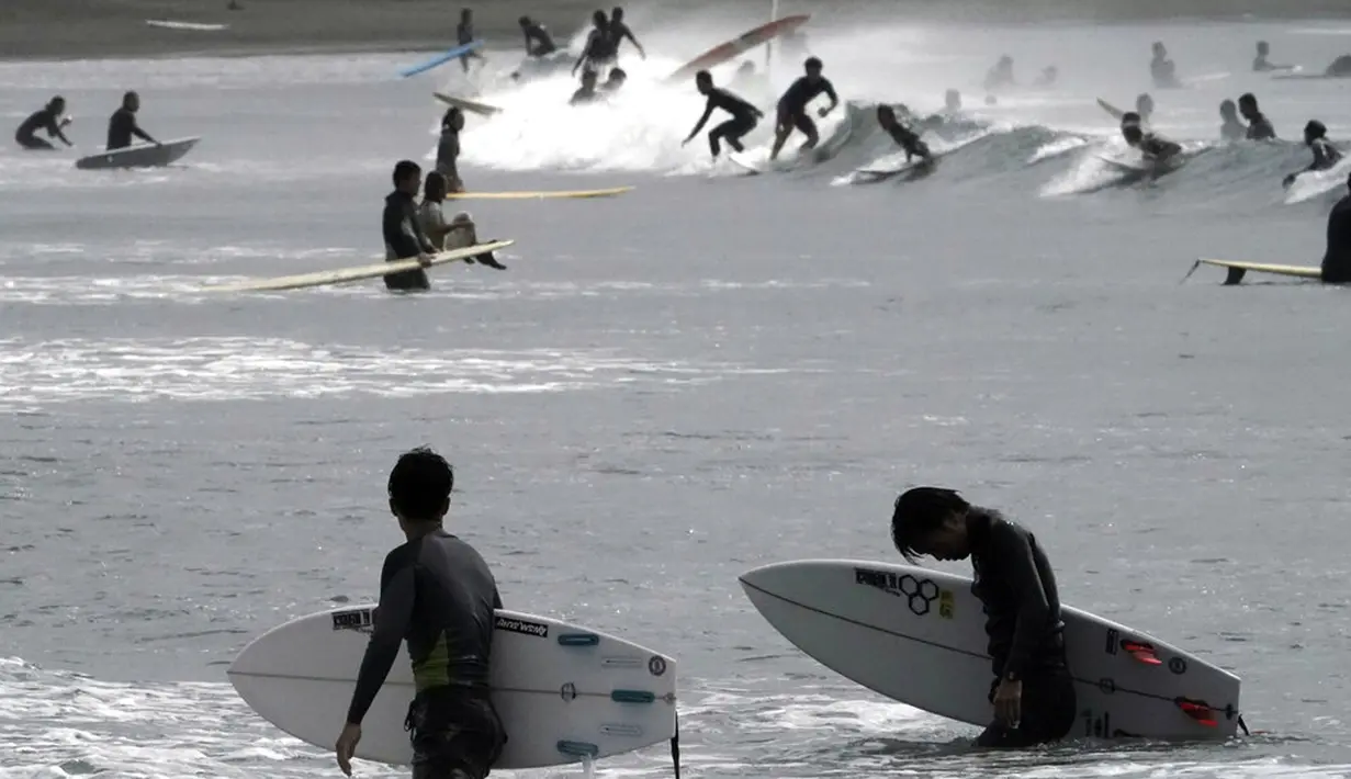 Orang-orang berselancar di pantai Katase-kaigan yang berangin, Fujisawa, Prefektur Kanagawa, selatan Tokyo, Jepang, Kamis (24/9/2020). Badai Tropis Dolphin bergerak di sepanjang pantai Pasifik Jepang. (AP Photo/Eugene Hoshiko)
