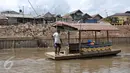Mami berada di atas perahu eretannya, Jakarta, Rabu (28/12). Meski penumpang tak seramai dulu, perahu eretan tetap bertahan diantara tembok beton normalisasi kali Ciliwung. (Liputan6.com/Yoppy Renato)