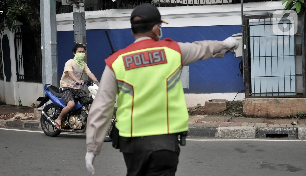 Petugas memberhentikan pengendara sepeda motor tanpa perlengkapan saat penindakan Pembatasan Sosial Berskala Besar (PSBB) di kawasan Menteng, Jakarta, Senin (13/4/2020). (merdeka.com/Iqbal S. Nugroho)