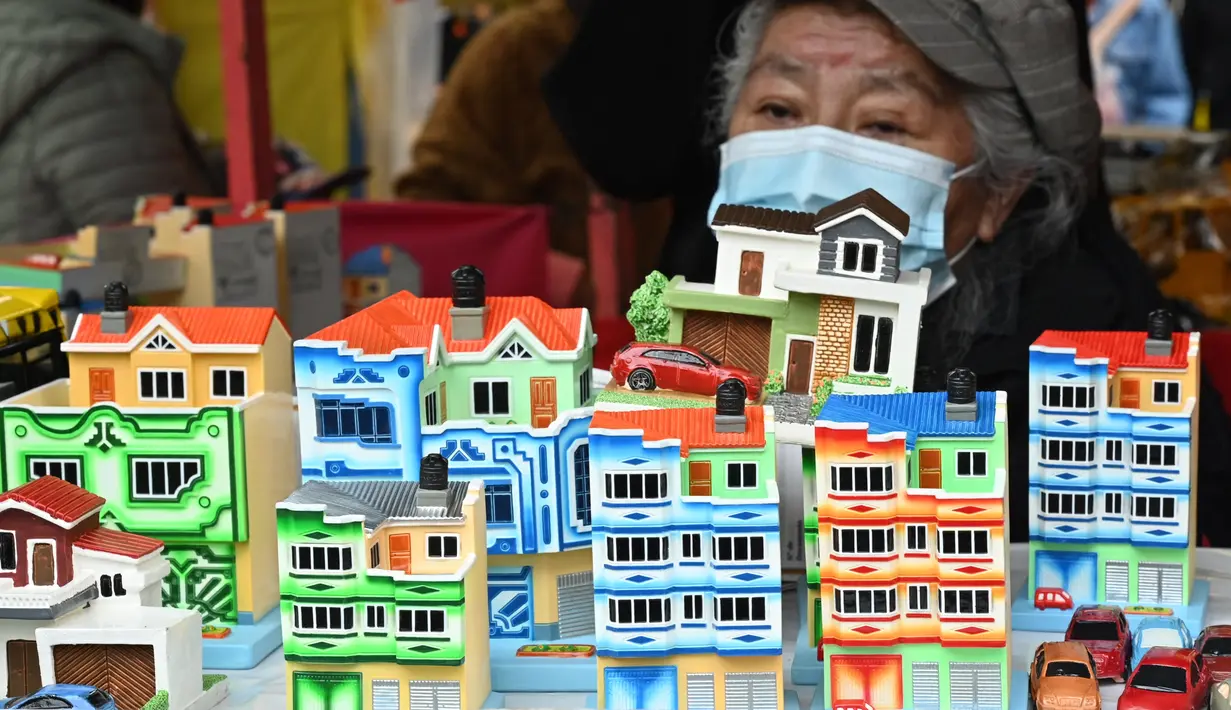 Seorang perempuan menjual bangunan mini di kios pinggir jalan selama Alasitas Fair tahunan di La Paz, Bolivia pada 24 Januari 2022. Orang-orang membeli replika kecil dari barang-barang yang ingin mereka peroleh sepanjang tahun, seperti rumah, mobil, dan kekayaan. (AIZAR RALDES/AFP)