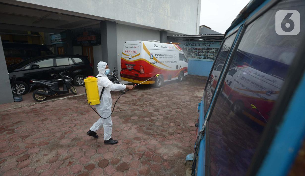 Petugas menyemprotkan cairan disinfektan kendaraan pelayanan Suku Dinas Sosial Jakarta Timur, Jumat (18/2/2022).  Sebanyak 6 orang yang terpapar Covid-19 sedang menjalani isolasi di rumah, sementara pelayanan ditutup selama tiga hari. (merdeka.com/Imam Buhori)