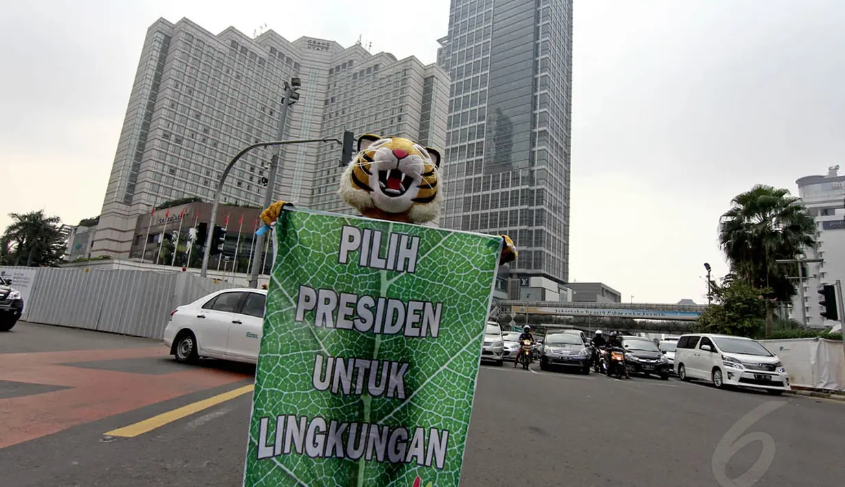 Aktivis Greenpeace berkostum harimau mengajak para pengguna jalan untuk memilih calon presiden cinta terhadap lingkungan di Bundaran HI, Jakarta, Minggu (11/5/14). (Liputan6.com/Faizal Fanani)