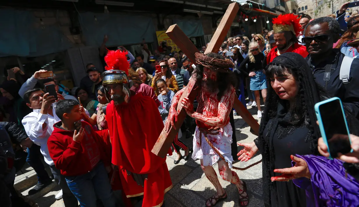 Seorang aktor berpakaian seperti Yesus Kristus memanggul salib saat melakukan prosesi Jalan Salib menyusuri Via Dolorosa menuju Gereja Makam Suci di Kota Tua Yerusalem, Jumat (19/4). Jalan Salib dilakukan untuk menggambarkan penderitaan Yesus Kristus selama penyaliban. (AP Photo/Ariel Schalit)