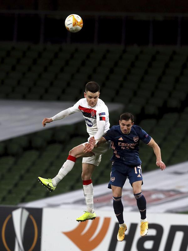Bek Arsenal, Cedric Soares berebut bola di udara dengan bek Dundalk, Darragh Leahy dalam pertandingan Grup B Liga Europa 2020/2021 di Stadion Aviva, Jumat (11/12/2020) dini hari WIB. Arsenal menang 4-2 saat bertandang di markas wakil Irlandia, Dundalk. (Brian Lawless/PA via AP)