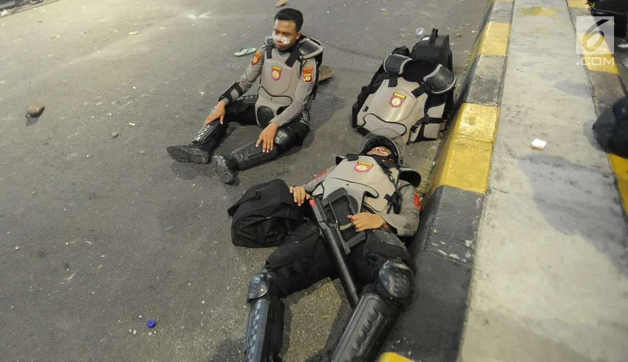 Anggota Dalmas BKO dari Polda Bali beristirahat usai mengamankan perusuh di atas fly over Slipi, Jakarta, Rabu (22/5/2019). Bentrokan panjang dengan para perusuh membuat anggota kepolisian yang berhadapan langsung kurang beristirahat. (merdeka.com/Arie Basuki)