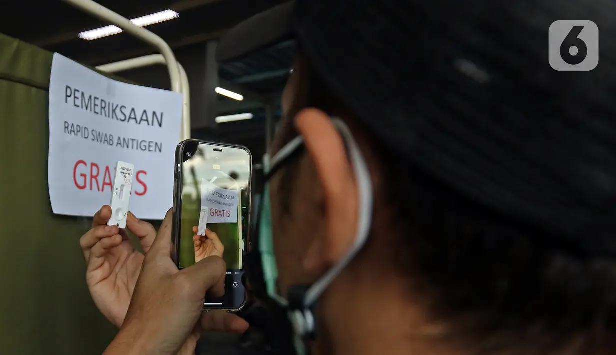 Calon penumpang memotret hasil tes antigen di Stasiun Manggarai, Jakarta, Senin (21/6/2021). PT KAI Commuter melakukan tes antigen secara acak kepada penumpang KRL guna mencegah penyebaran COVID-19. (Liputan6.com/Herman Zakharia)