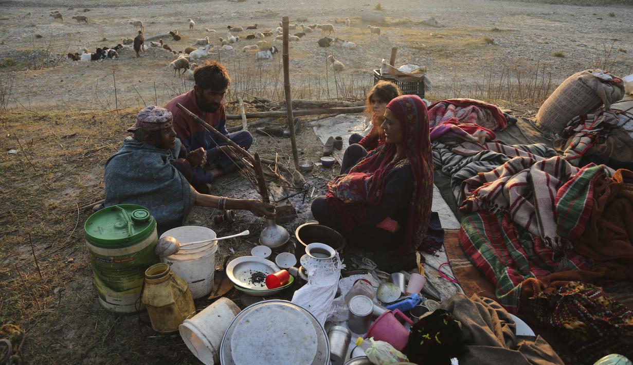 Sebuah keluarga nomaden berhenti sementara di jalan raya Jammu-Srinagar di Nagrota, di pinggiran Jammu, India, Selasa (9/11/2021). Anggota suku tersebut pindah dari perbukitan untuk menghindari musim dingin. (AP Photo/Channi Anand)