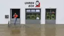 Seorang pria mencoba menumpahkan air dengan ember dari toko arlojinya di jalan dan rumah-rumah yang tergenang banjir di pusat kota Passau, Bavaria, wilayah selatan Jerman, pada 4 Juni 2024. (Michaela STACHE/AFP)