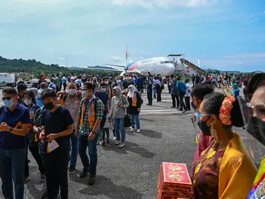 Turis domestik turun dari pesawat Boeing 738 Malaysia Airlines setelah mendarat di Langkawi dari Bandara Internasional Kuala Lumpur saat pulau liburan dibuka kembali untuk turis domestik menyusul penutupan karena pembatasan untuk menghentikan penyebaran Covid-19 (16/9/2021). (AFP/Mohd Rasfan)