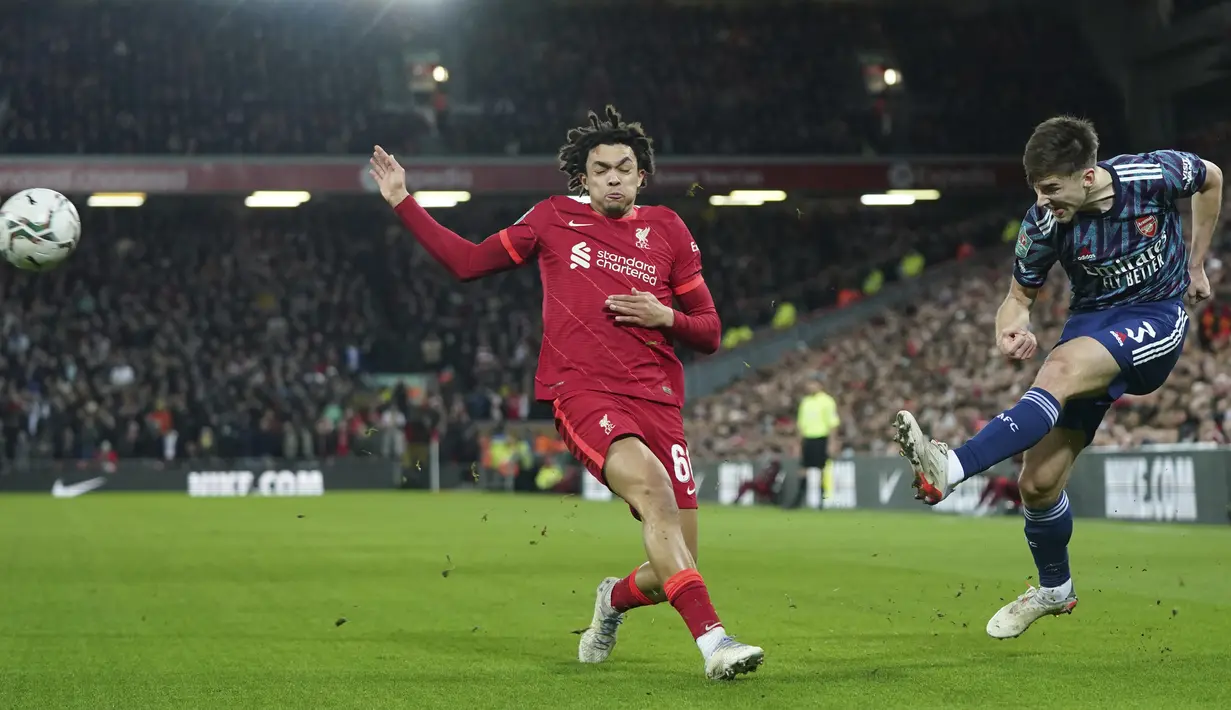 Bek Arsenal Kieran Tierney menendang bola di depan bek Liverpool Trent Alexander-Arnold pada leg pertama semifinal Piala Liga di Stadion Anfield , Jumat (14/1/2022) dinihari WIB. Arsenal dipkasa bermain imbang tanpa gol oleh Liverpool. (AP Photo/Jon Super)