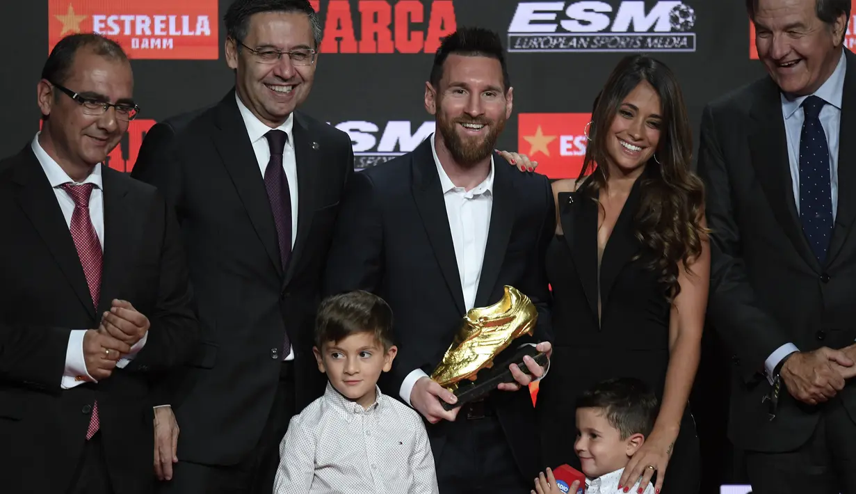 Pemain Barcelona, Lionel Messi (tengah) berpose bersama istrinya Antonella Roccuzzo dan putra-putranya Thiago dan Mateo setelah menerima trofi Sepatu Emas keenamnya selama acara penyerahan di Antiga Fabrica Estrella Damm, Barcelona, Spanyol (16/10/2019). (AFP Photo/Josep Lago)
