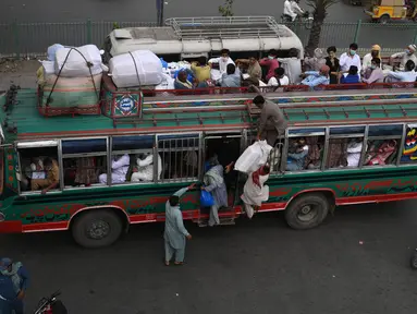 Warga menaiki bus saat mereka melakukan perjalanan ke kampung halaman mereka menjelang perayaan Idul Fitri di Lahore (7/5/2021). Lebaran Idul Fitri jatuh pada 13 Mei 2021. (AFP Photo/Arif Ali)