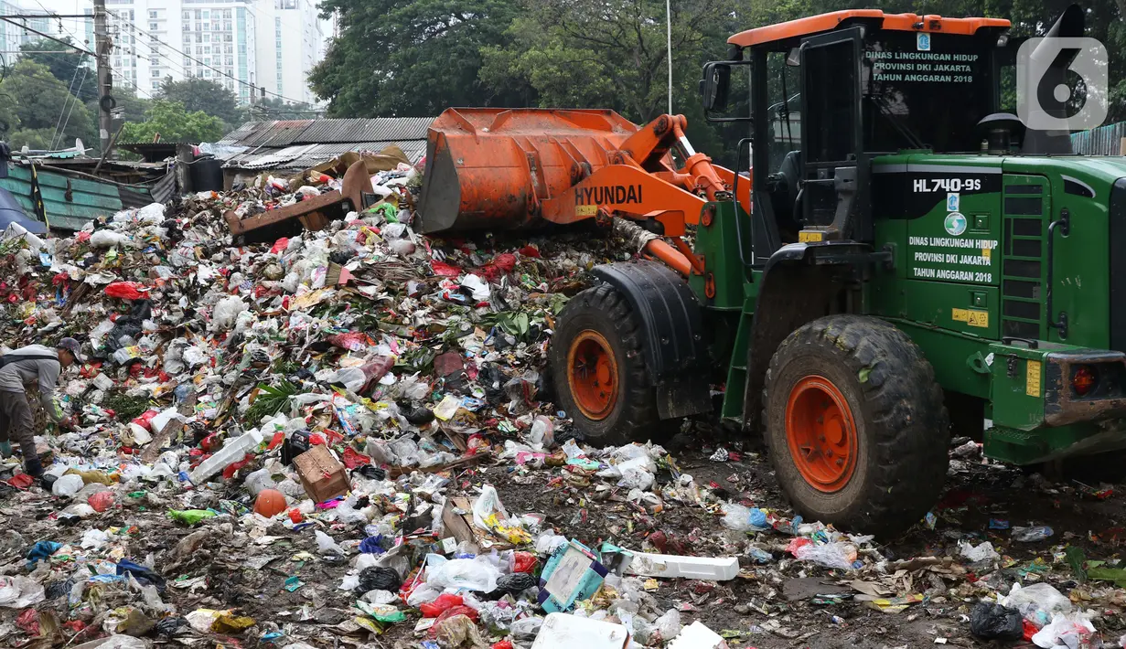 Petugas mengoperasikan alat berat untuk memindahkan sampah di Tempat Pembuangan Sementara Kalibata, Jumat (10/4/2020). Kadis Lingkungan Hidup DKI Jakarta, Andono Warih mengatakan terjadi penurunan tonase sampah rata-rata 620 ton per hari selama penerapan WFH. (Liputan6.com/Helmi Fithriansyah)