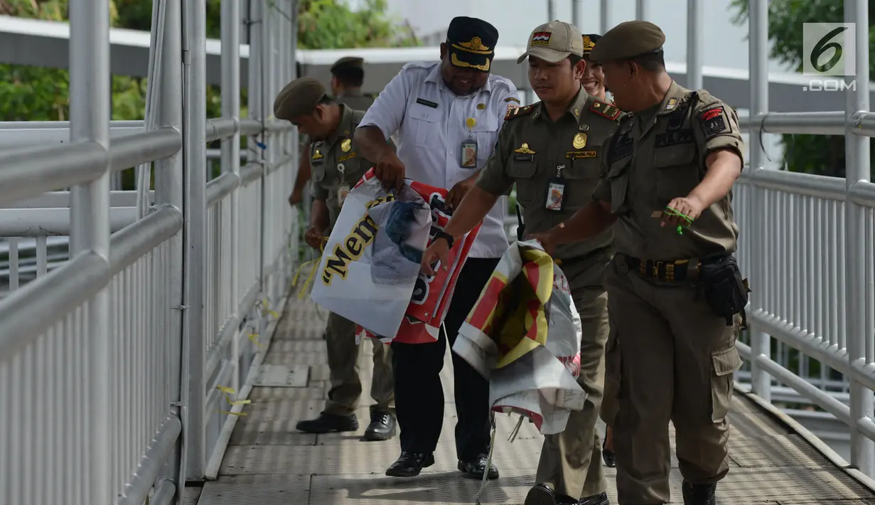 Petugas Satpol PP membawa APK Pemilu 2019 di Kawasan Jalan Pemuda, Jakarta, Rabu (13/3). APK Pemilu 2019 yang terpasang pada JPO dibersihkan hal tersebut mengganggu dan melanggar aturan pemasangan dari komisi Pemilihan umum. (merdeka.com/Imam Buhori)