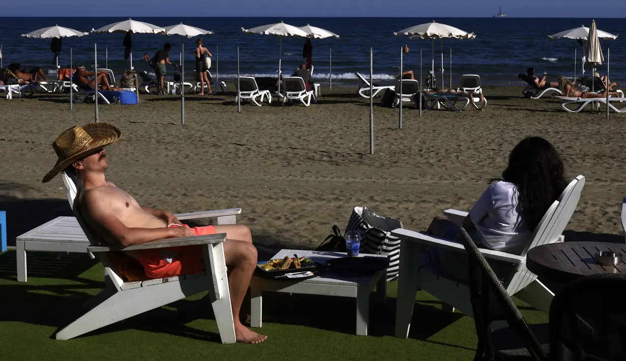 Sepasang suami istri menikmati cuaca hangat di pantai Makenzi di selatan kota Larnaca, Siprus, Senin (8/11/2021). Cuaca hangat tersebut membuat banyak orang untuk mencapai Mediterania timur pantai negara kepulauan. (AP Photo/Petros Karadjias)