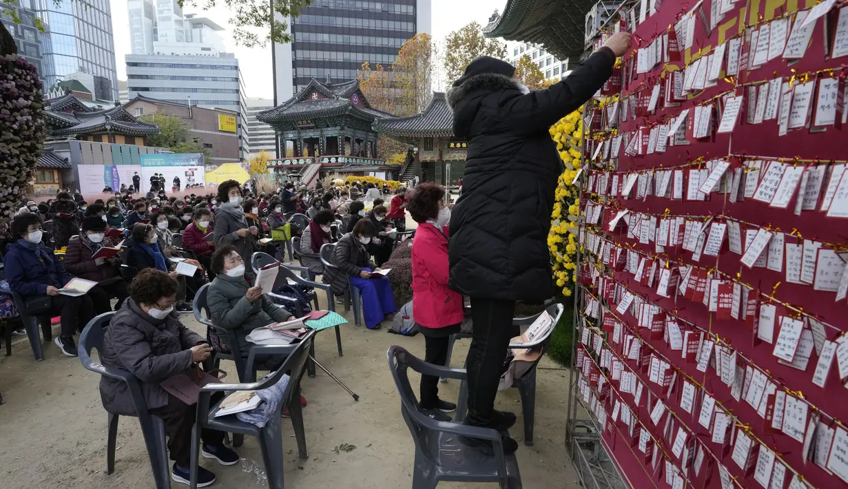 Seorang wanita menggantungkan kertas untuk mendoakan keberhasilan anaknya dalam ujian masuk perguruan tinggi di kuil Buddha Jogyesa, Seoul, Rabu (17/11/2021). Sekitar 500.000 siswa SMA di Korea Selatan diperkirakan akan mengikuti Tes Kemampuan Skolastik Perguruan Tinggi. (AP Photo/Ahn Young-joon)