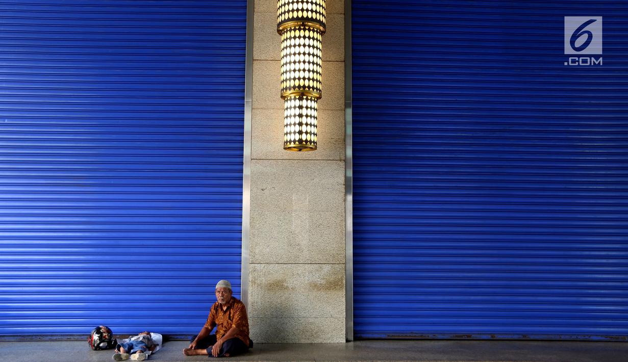 Seorang pria dan anak kecil beristirahat di depan kios yang tutup di Blok B Pasar Tanah Abang, Jakarta, Selasa (27/6). Dalam rangka libur lebaran, Pasar Tanah Abang tutup mulai Minggu (25/7) hingga buka kembali pada 3 Juli 2017. (Liputan6.com/Johan Tallo)