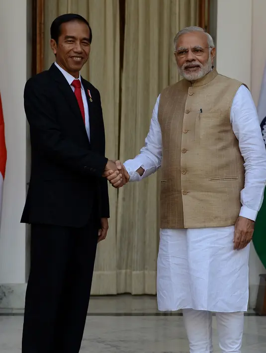 Presiden Joko Widodo (Jokowi) berjabat tangan dengan PM India Narendra Modi sebelum melakukan pertemuan bilateral di Hyderabad House, New Delhi, Senin (12/12). Ini pertama kalinya Presiden Jokowi melakukan kunjungan kenegaraan ke India. (Money SHARMA/AFP)
