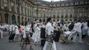 Peserta membawa kursi dan perlengkapan lain ketika mengikuti 'Diner en blanc' atau 'Makan Malam Putih' di Place Vendome, Paris, Rabu (8/6). Untuk  mendapatkan undangan, peserta harus mengenal seorang anggota organisasi Diner en Blanc. (PHILIPPE LOPE/AFP)