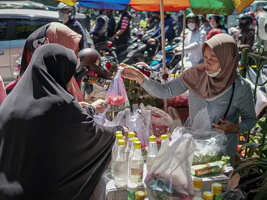 Penjual bunga tabur melayani pembeli di TPU Karet Tengsin, Jakarta, Minggu (27/3/2022). Sebagian warga memanfaatkan waktu jelang Ramadan menjadi penjual bunga tabur musiman untuk memenuhi kebutuhan ziarah ke makam yang dijual Rp 5.000 - Rp 20.000 per kantong plastik. (Liputan6.com/Faizal Fanani)