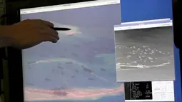 Seorang anggota Angkatan Laut AS memberitahukan kontruksi yang dilakukan Cina untuk mereklamasi terumbu karang Fiery Cross Reef di laut Cina selatan, (21/5/2015). Kabarnya Pesawat Militer Cina telah mendarat pertama di pulau itu. (REUTERS / A.S . Navy)