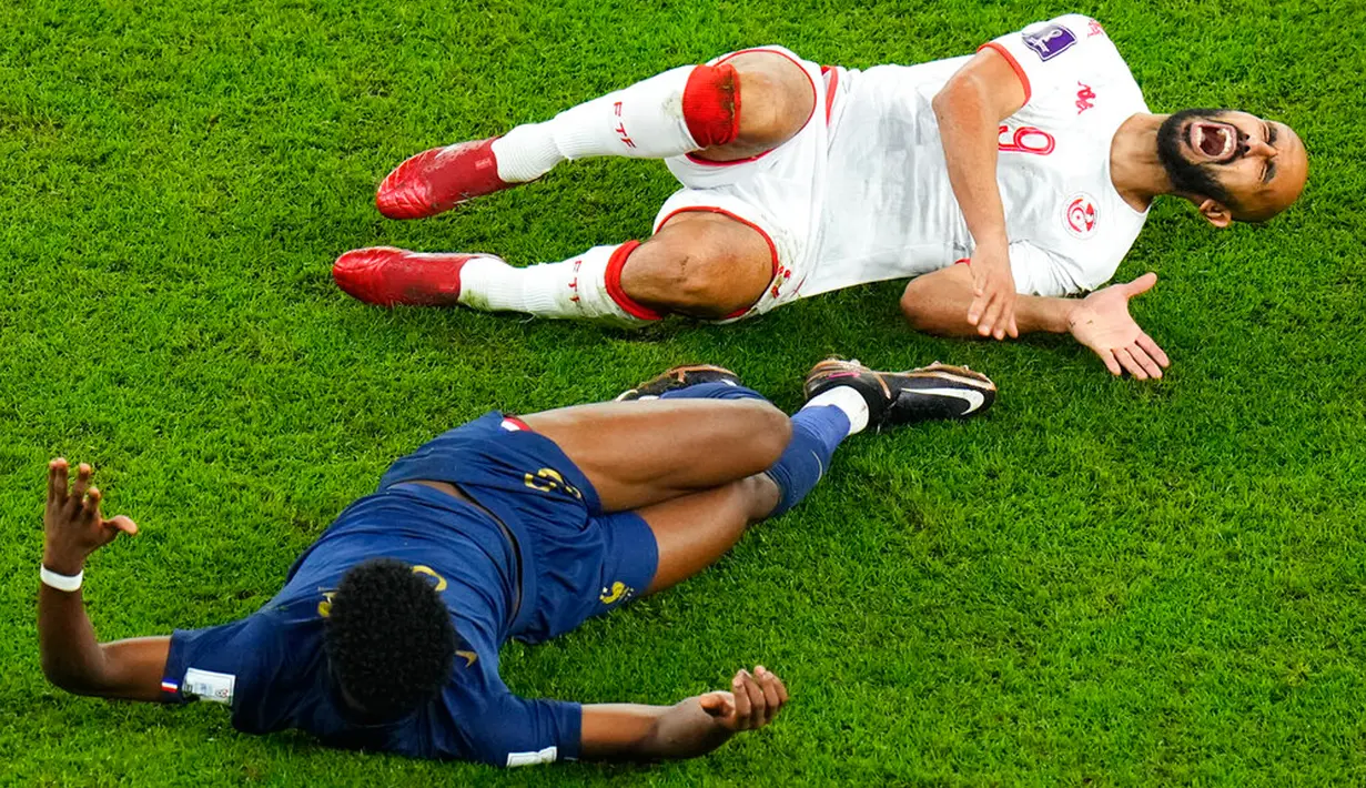 Pemain Tunisia Issam Jebali (atas) meringis kesakitan di samping pemain Prancis Matteo Guendouzi pada pertandingan sepak bola Grup D Piala Dunia 2022 di Stadion Education City, Al Rayyan, Qatar, 30 November 2022. Prancis menjuarai Grup D Piala Dunia 2022 meski kalah dari Tunisia 1-0. (AP Photo/Petr David Josek)