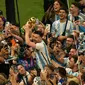 Pemain Argentina Lionel Messi (tengah) memegang trofi juara saat merayakan bersama para penggemar setelah Argentina mengalahkan Prancis pada pertandingan sepak bola final Piala Dunia 2022 di Stadion Lusail, Lusail, Qatar, 18 Desember 2022. Argentina menang 4-2 dalam adu penalti setelah pertandingan berakhir imbang 3 -3. (AP Photo/Francisco Seco)