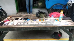 Brang bukti yang ditemukan polisi saat penggerebekan Kampung Boncos, Kota Bambu Selatan, Palmerah Jakarta Barat, Rabu (7/2). Polisi menyita 10 paket sabu, bahan campuran ganja, uang ratusan ribu, dan senjata tajam. (Liputan6.com/ Ady Anugrahadi)