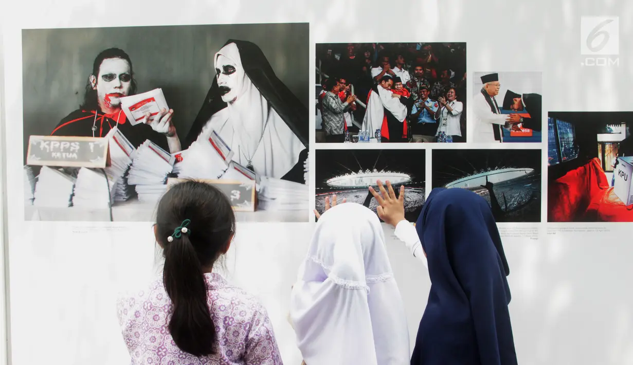 Siswa SD Negeri Menteng 01 mengamati karya foto yang dipamerkan dalam pameran fotografi Rekam Jakarta di Taman Menteng, Kamis (29/8/2019). Kegiatan tersebut dalam rangka edukasi bagi siswa mengenal profesi foto jurnalistik. (Liputan6.com/Marsha Aulia)
