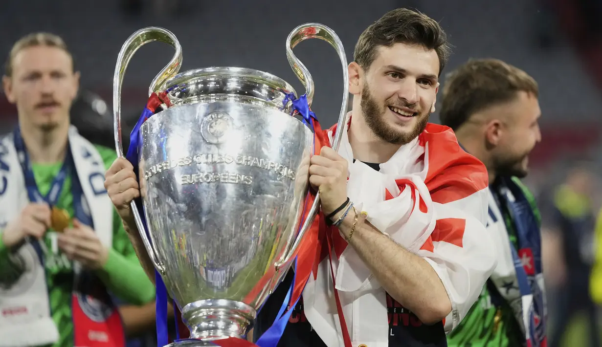 Pemain PSG, Khvicha Kvaratskhelia berpose dengan trofi Liga Champions 2024/2025 setelah timnya menjadi juara dengan mengalahkan Inter Milan di Allianz Arena, Munchen, Jerman, Minggu (01/06/2025) dini hari WIB. (AP Photo/Luca Bruno)