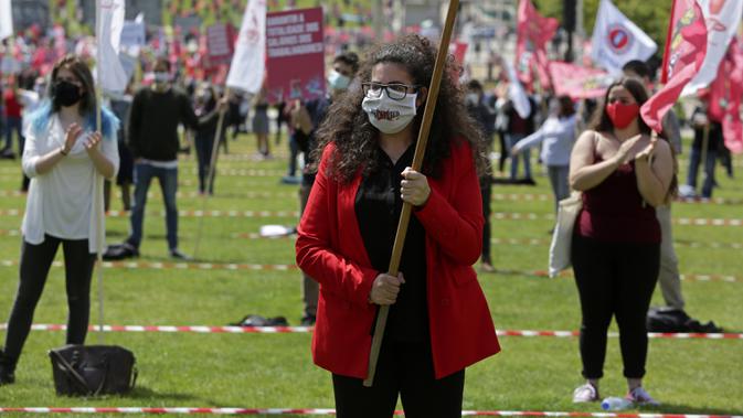 Delegasi serikat pekerja mengenakan masker sambil membawa bendera saat memperingati Hari Buruh di tengah pandemi COVID-19 di Lisbon, Portugal, Jumat (1/5/2020). Aksi ini sudah mendapat persetujuan Kementerian Kesehatan dan Dalam Negeri Portugal. (AP Photo/Armando Franca)