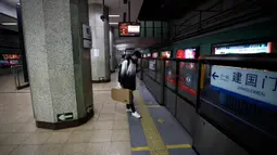 Seorang pria mengenakan masker saat berdiri sendirian menunggu kereta di stasiun bawah tanah di Beijing, China, Senin (17/2/2020). Kendati berjarak 1.055 kilometer dari Wuhan yang dikarantina akibat virus corona atau COVID-19, aktivitas warga di Beijing terlihat sepi. (AP Photo/Andy Wong)