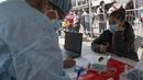 Seorang wanita menunggu untuk swab COVID-19 di sebuah pusat kesehatan darurat di sebuah jalan di pusat kota Lima, Rabu (5/1/2022). Peru melaporkan negara itu secara resmi menghadapi gelombang ketiga COVID-19 karena peningkatan kasus infeksi setelah perayaan Natal dan Tahun Baru. (Cris BOURONCLE/AFP)