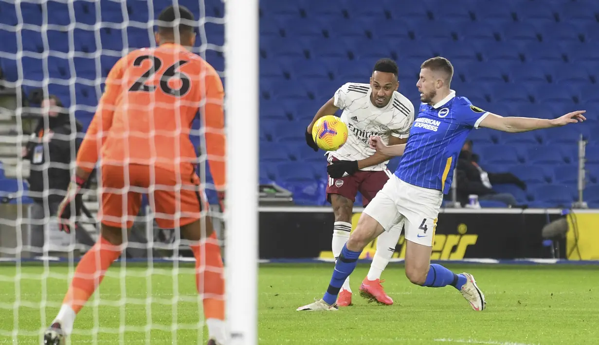 Penyerang Arsenal, Pierre-Emerick Aubameyang menembak bola dari kawalan pemain Brighton & Hove Albion, Adam Webster pada pertandingan lanjutan liga Inggris di stadion Falmer, Inggris, Rabu (30/12/2020). Meriam London menang tipis 1-0 atas Brighton. (Neil Hall/Pool via AP)