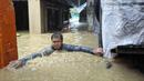 Seorang pria mengatasi banjir setinggi leher di desanya yang disebabkan oleh Topan Doksuri di kota Laoag, provinsi Ilocos Norte, Filipina utara, Rabu, 26 Juli 2023. (AP Photo/Bernie Sipin Dela Cruz)