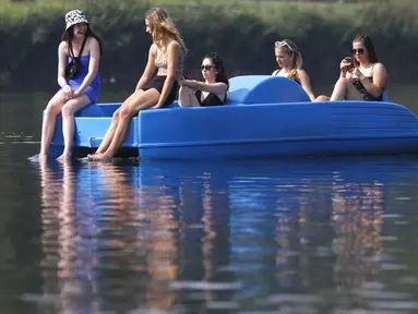 Sejumlah wanita bersantai di perahu kayuh di The Serpentine di Hyde Park di London, Rabu, (12/8/2020). Peringatan badai masih berlaku untuk sebagian besar Inggris pada hari Rabu, sementara suhu tinggi diperkirakan lagi di banyak bagian Inggris. ( AP Photo / Kirsty Wigglesworth)