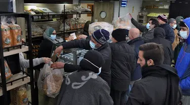 Orang-orang mengantre untuk mendapatkan roti di dalam toko roti di pinggiran selatan Beirut, Dahiyeh, Lebanon, pada 15 Maret 2022. Melonjaknya harga energi dan makanan yang dipicu oleh invasi Rusia ke Ukraina mendorong beberapa negara Timur Tengah ke tepi jurang. (AP Photo/Bilal Hussein)