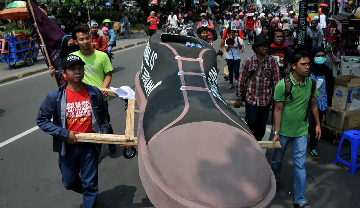 Belasan wartawan yang tergabung dalam Aliansi Jurnalis Independen (AJI) membawa sepatu raksasa sebagai simbol demonstrasi menuntut perbaikan kesejahteraan wartawan, Kamis (1/5/14). (Liputan6.com/Johan Tallo) 