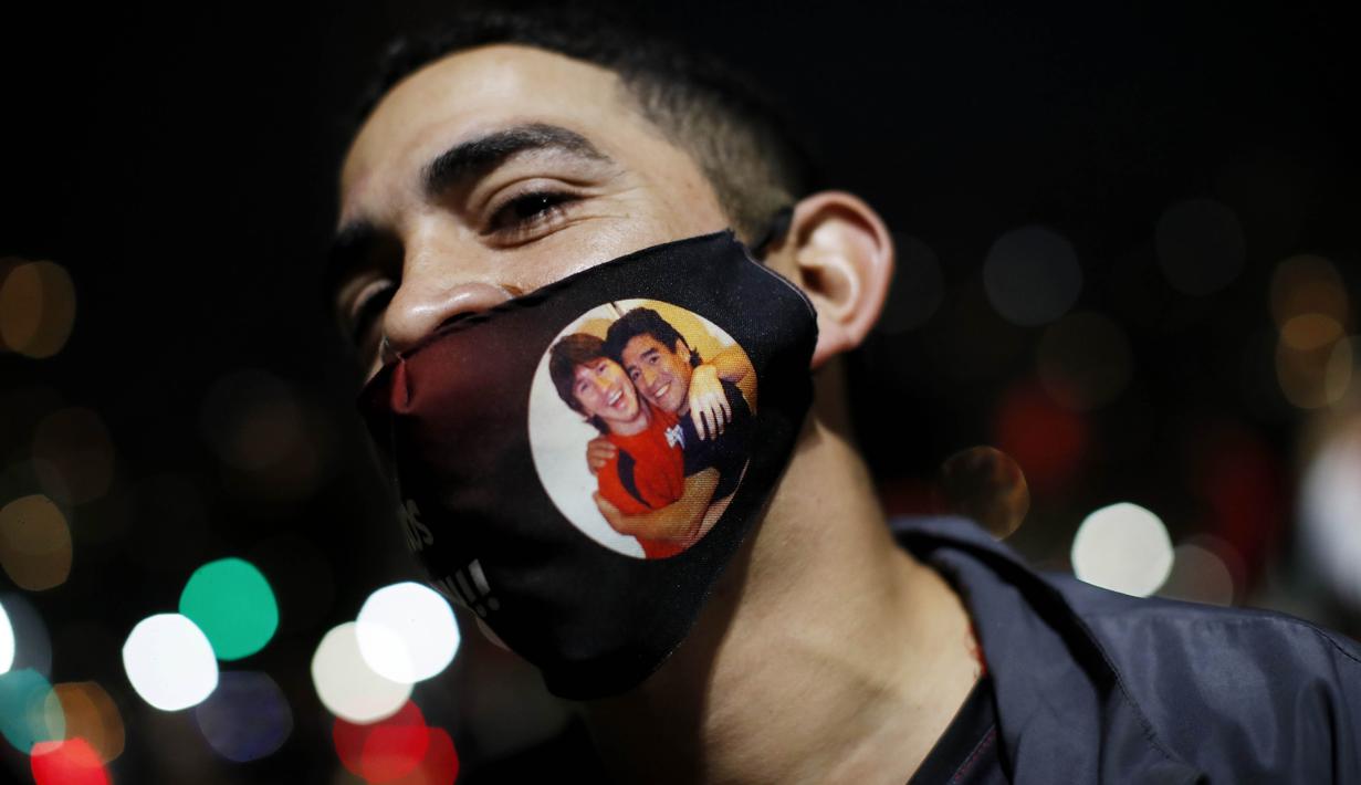 Suporter Newell's Old Boys memakai masker bergambar Messi dan Maradona saat melakukan aksi turun ke jalan di Rosario, Argentina, Kamis (27/8/2020). Dalam aksi tersebut mereka meminta klub memboyong kembali Lionel Messi. (AP Photo/Natacha Pisarenko)
