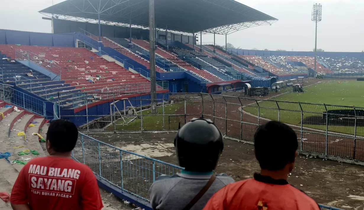 Orang-orang memeriksa kerusakan setelah tragedi kerusuhan pada pertandingan sepak bola antara Arema Vs Persebaya di Malang, Jawa Timur, Minggu (2/10/2022). Korban meninggal dunia dalam kejadian tersebut bertambah dua orang menjadi 129 orang. (AP Photo/Hendra Permana)