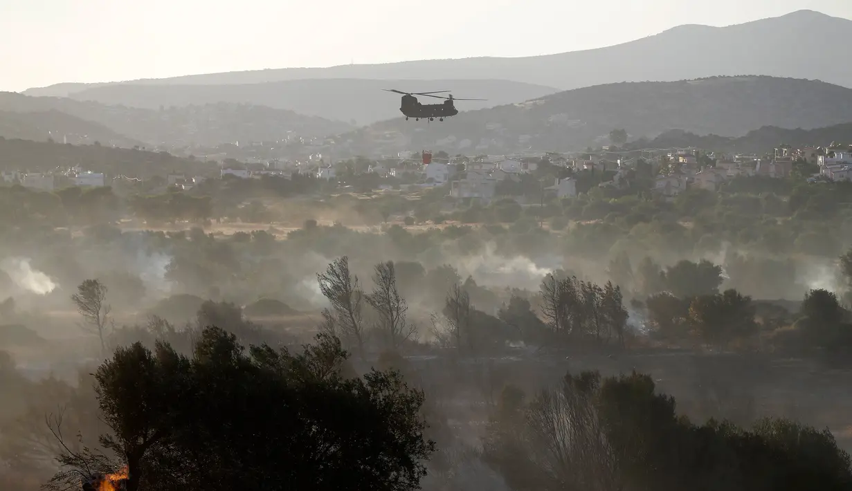 Helikopter terbang di atas lokasi kebakaran lahan usai upaya pemadaman di daerah Kalyvia, Athena, Senin (31/7). Saat musim panas, kebakaran hutan sering terjadi di Yunani dan pernah menelan korban sebanyak 20 orang tewas. (AP/Thanassis Stavrakis)