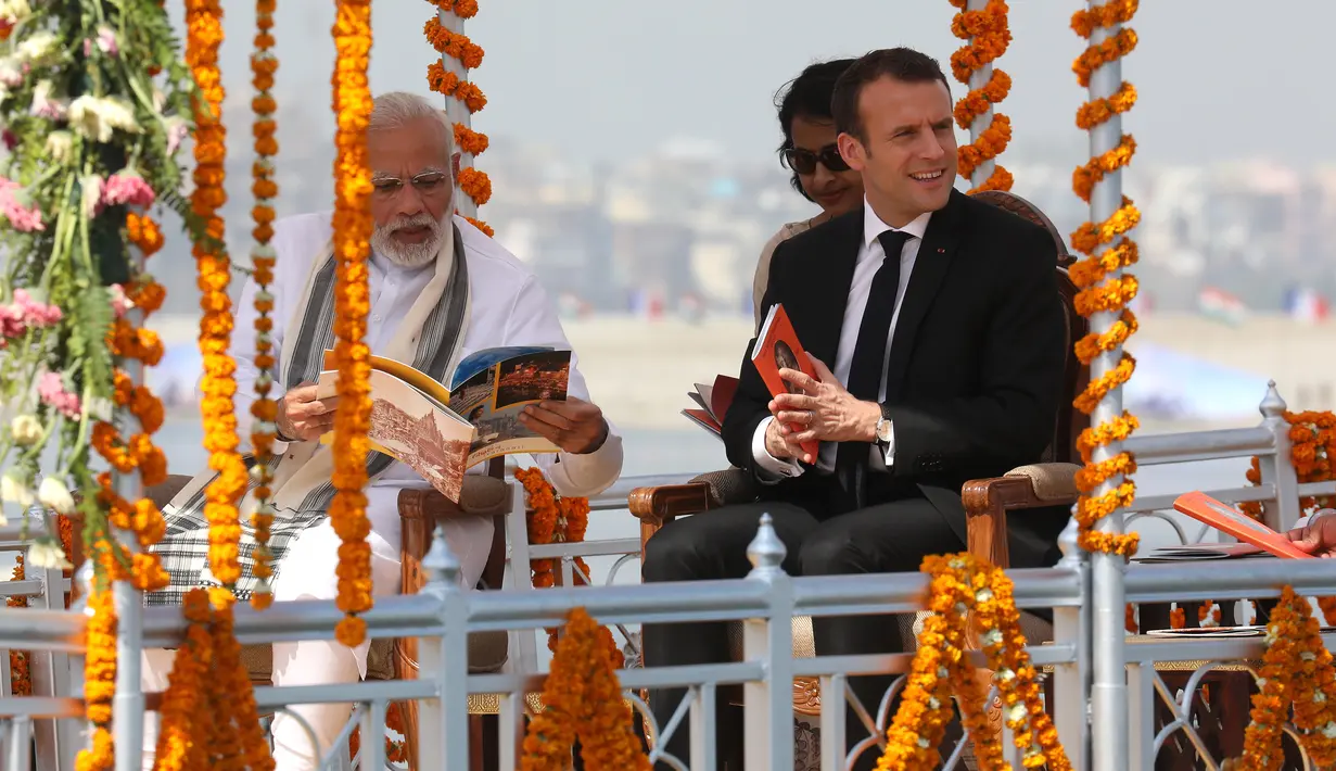 Presiden Prancis Emmanuel Macron (kanan) ditemani Perdana Menteri (PM) India Narendra Modi (kiri) menyusuri Sungai Gangga di Kota Varanasi, India, Senin (12/3). Macron mengunjungi India selama empat hari. (Ludovic MARIN/POOL/AFP)