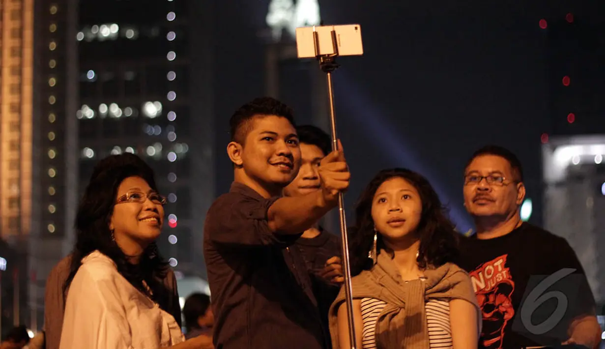 Sejumlah warga mengambil foto selfie saat akan merayakan malam pergantian tahun di kawasan Bundaran HI, Jakarta, Rabu (31/12/2014). (Liputan6.com/Faizal Fanani)
